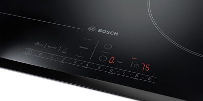 Nahaufnahme eines Bosch-Induktionskochfelds mit Leuchtelementen und Bedienelementen. Nahaufnahme eines Bosch-Induktionskochfelds mit Leuchtelementen und Bedienelementen.